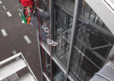 Fassadenkletterer reinigt Glasfront am hängenden Seil, Arbeit am Seil