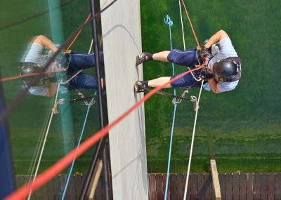 Glasreinigung am Seil in der Höhe, Gebäudereinigung mit Fassadenkletterer und Arbeit am hängenden Seil