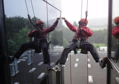 Fassadenkletterer reinigt Glasfront am hängenden Seil, Seilarbeit